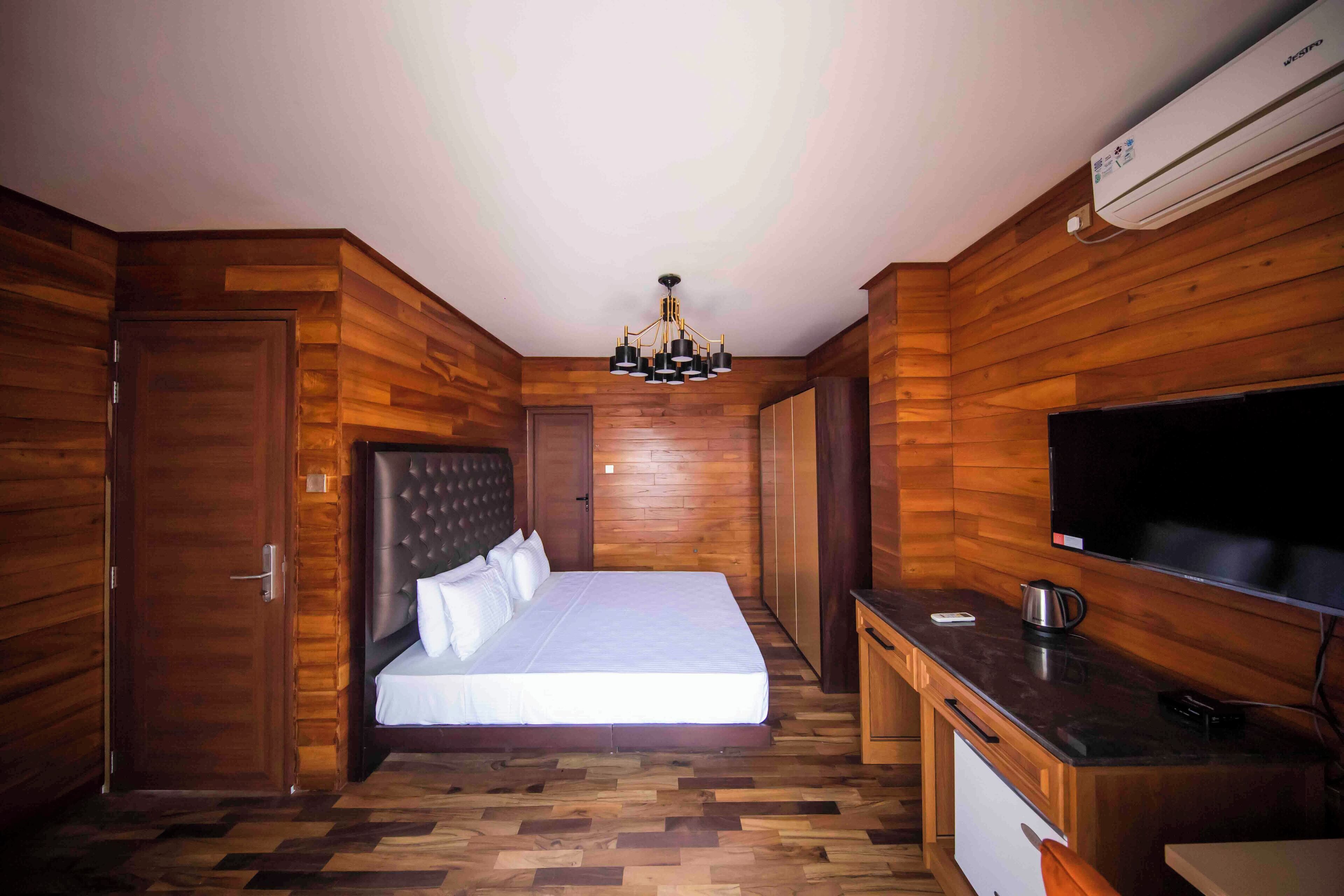 Una habitación con cama, escritorio, televisor y aire acondicionado.
