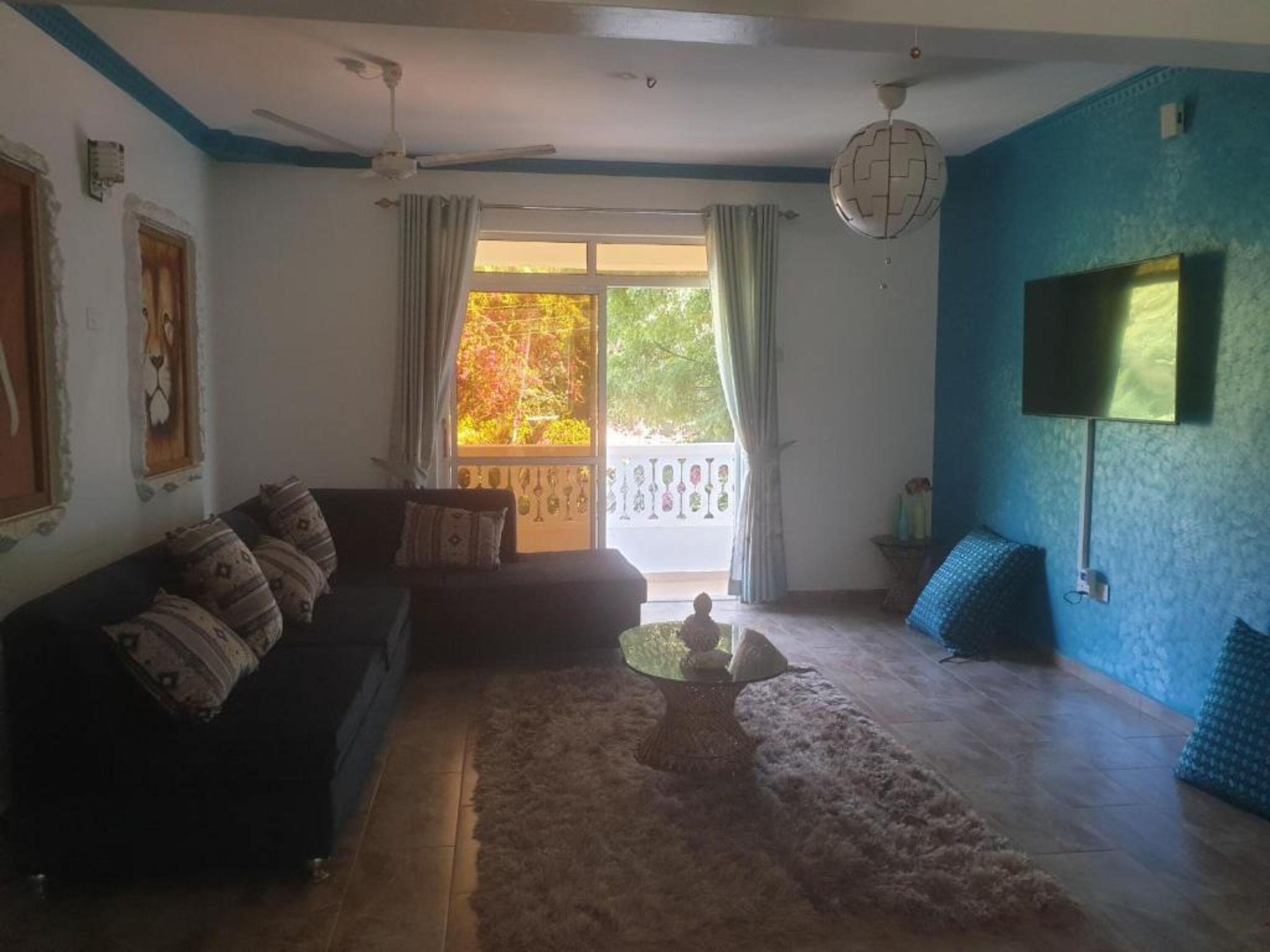 A living room with a dark-colored sofa, a coffee table, and a blue accent wall.