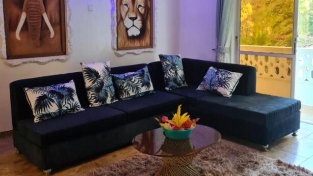 Een moderne woonkamer met een hoekbank, een decoratief vloerkleed en twee grote wanddecoraties met dierenmotieven.