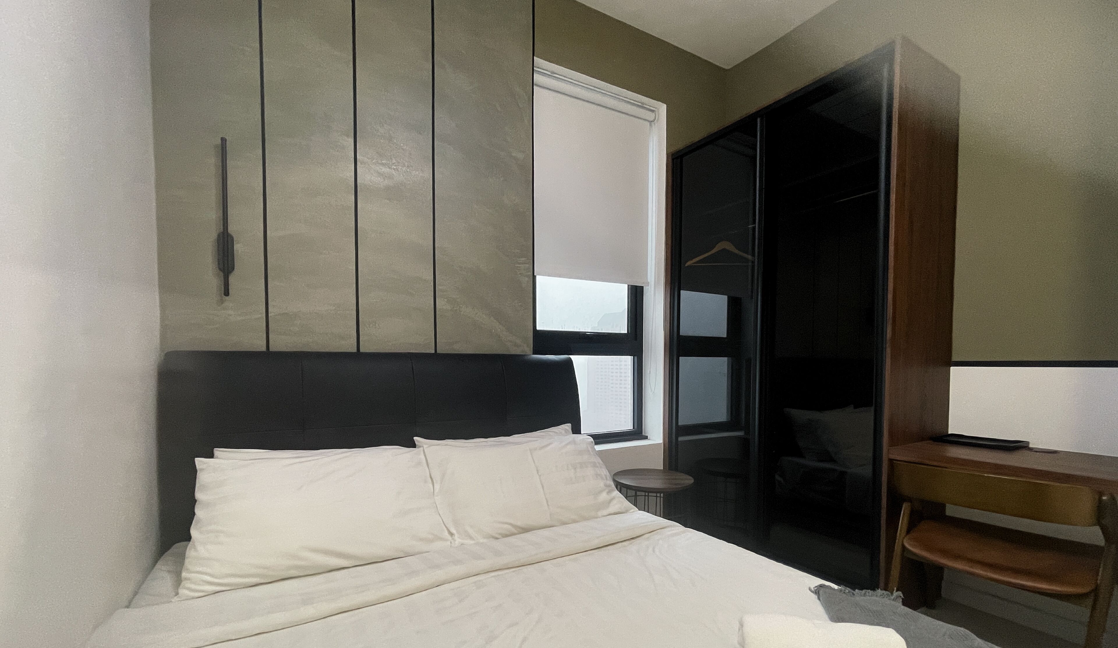 Un dormitorio moderno con una cama grande, un escritorio pequeño y un armario corredero.