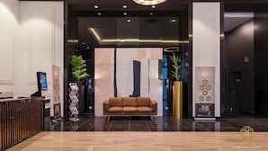 Una hall moderna con una reception, un divano in pelle marrone e un ampio murale astratto.
