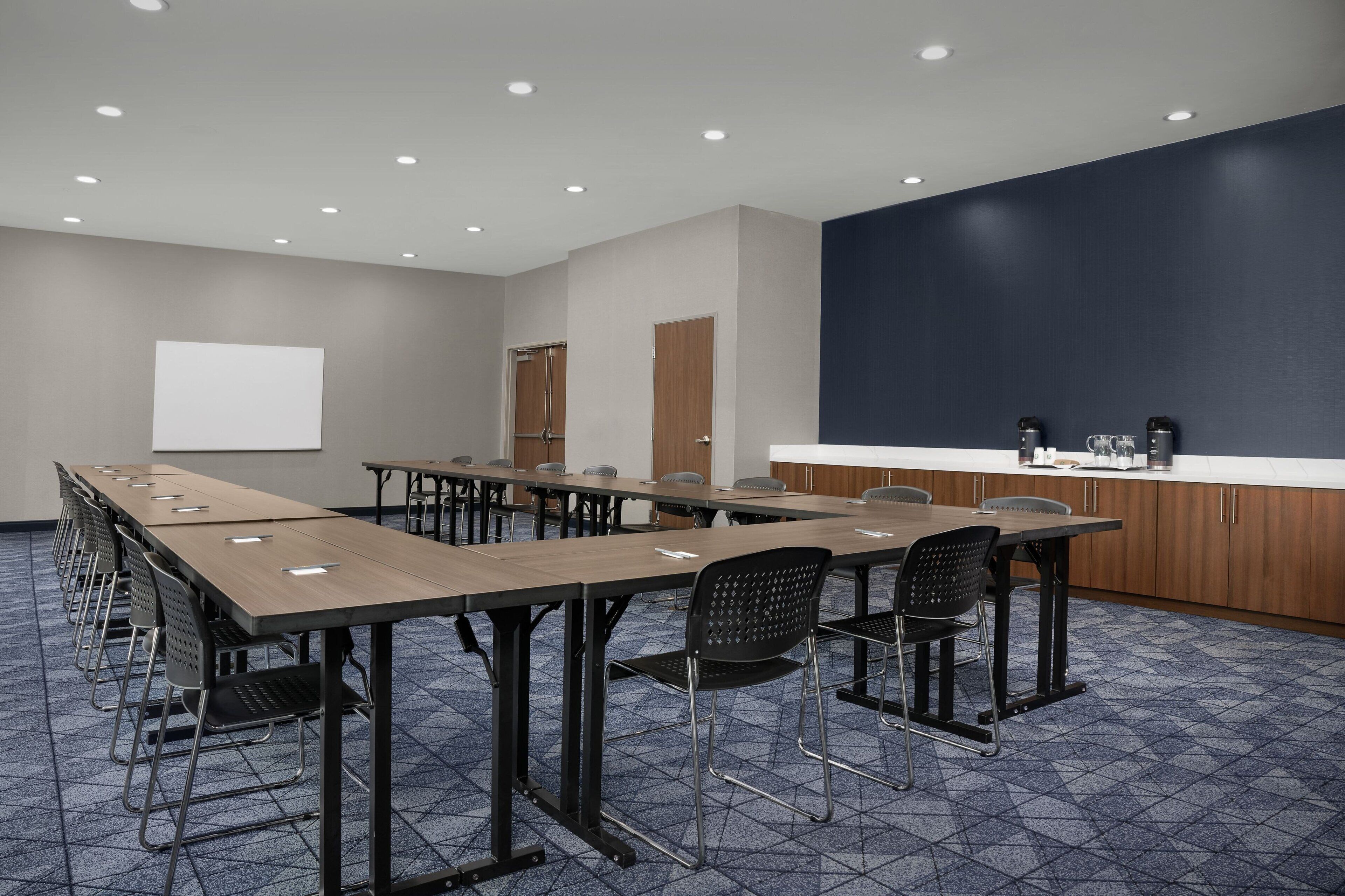 A conference room with a long table, chairs, a whiteboard, and a coffee station.