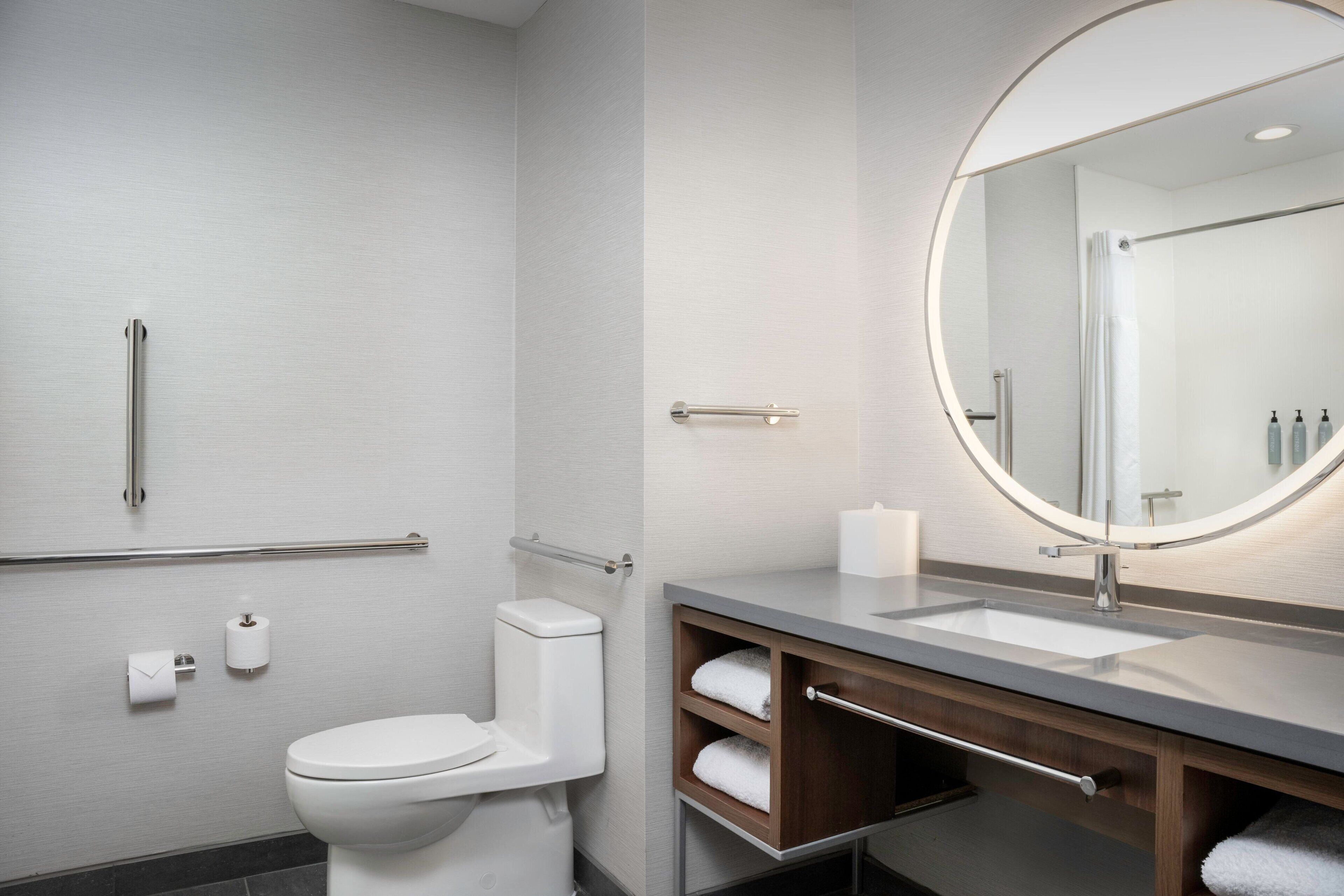 A modern bathroom with a toilet, sink, and mirror.