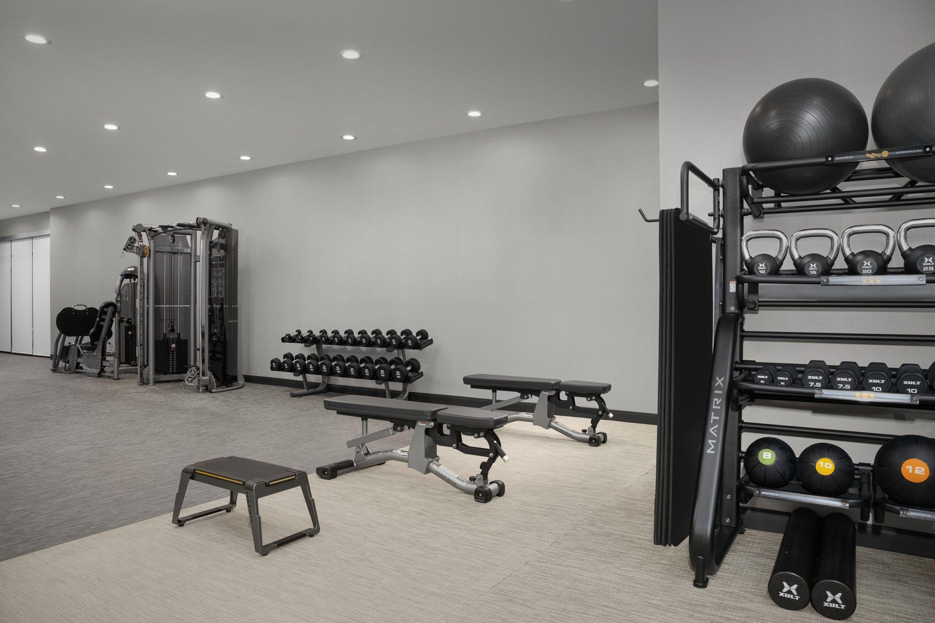 A gym with weightlifting equipment, benches, and dumbbells.