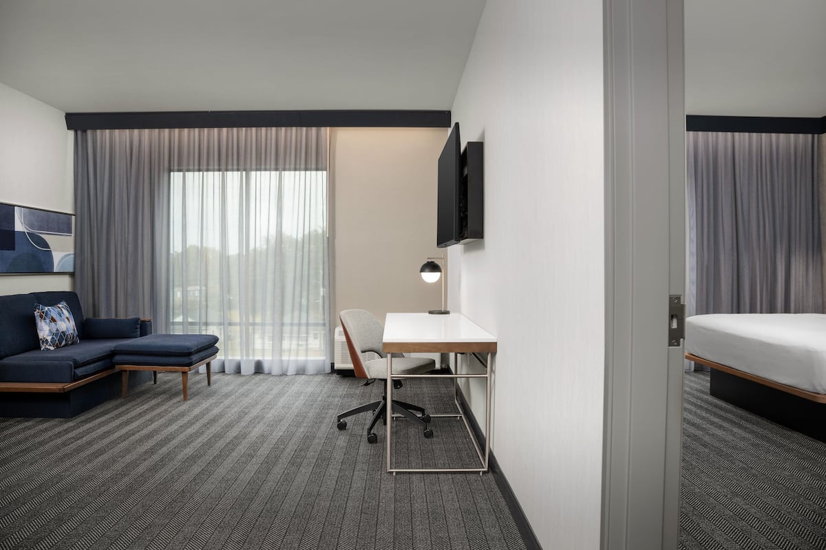 Une chambre d’hôtel comprenant un canapé d’angle, un bureau, un téléviseur à écran plat et un lit.