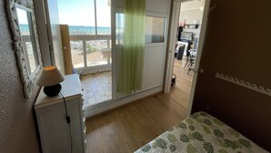 Un dormitorio con balcón, un escritorio con lámpara y vistas a la playa.