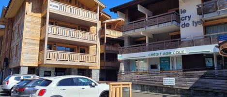 A multi-story wooden building with balconies, a sign for 'le cry de lys', and a 'CRÉDIT AGRICOLE' bank.