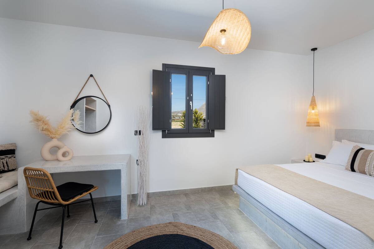 Un dormitorio moderno con una cama, un escritorio, una silla, un espejo y una ventana con contraventanas.