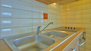 A modern kitchen with two stainless steel sinks, wooden countertops, and white tiled walls. - Air-conditioned apartment Umag (Umag)