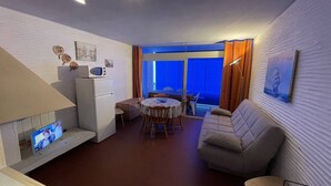 A compact living space with a kitchenette, a sofa, a dining area, and a large window. - Beachfront Apartment, Ocean View, 2 Rooms, 5 Guests, Secure Parking, Pets Welcome (Saint-Cyprien)