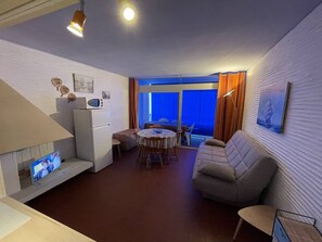 Um espaço compacto com cozinha compacta, sofá, área de refeições e uma janela grande.