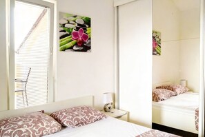 Quarto de hotel com cama, mesa de cabeceira, luminária e duas imagens penduradas na parede.
