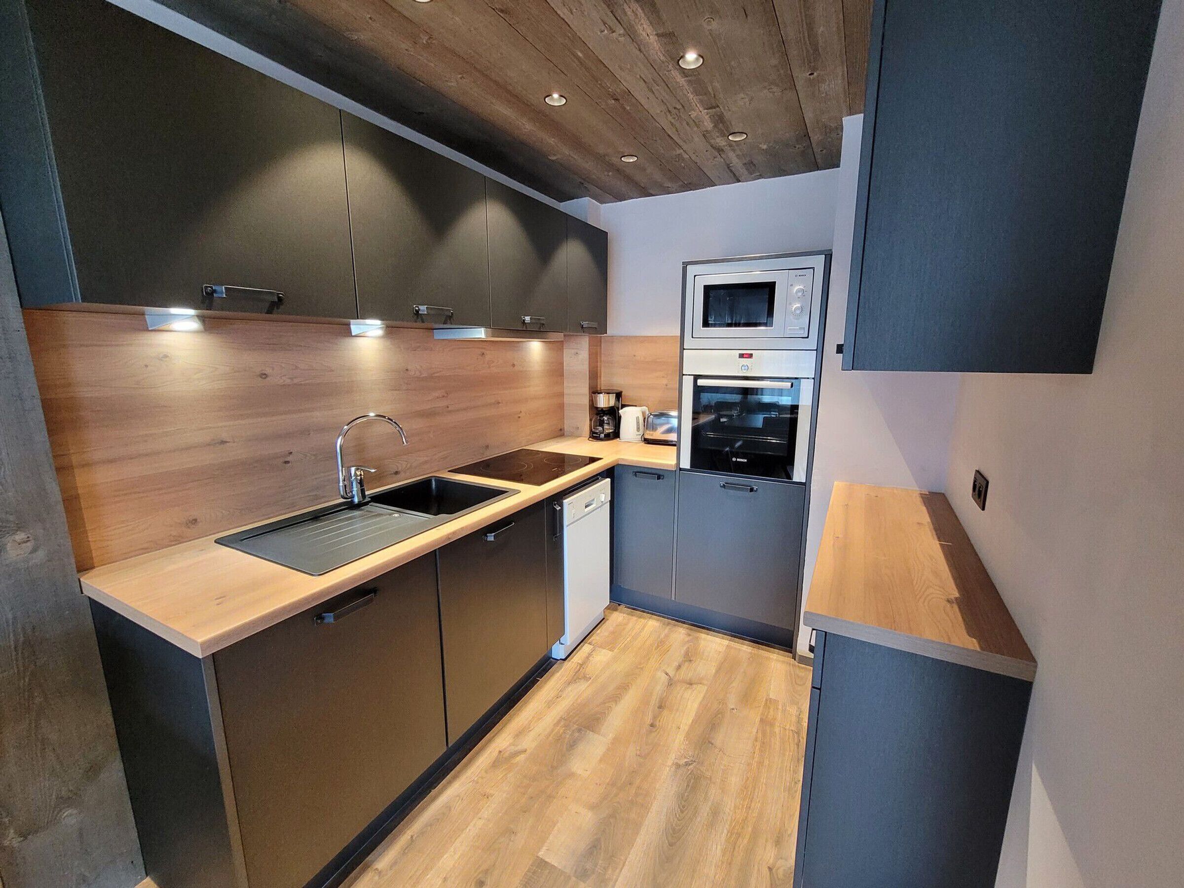 Eine kleine Küche mit einer Holz Arbeitsplatte, Edelstahlgeräten und einem eingebauten Backofen.