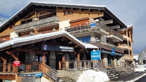A multi-story ski resort building with wooden balconies and a sign for Precision Ski Jordan's Sports.