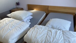 Hotellihuone, jossa on kaksi sänkyä, ja molemmissa on valkoiset vuodevaatteet ja puinen pääty.