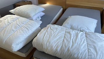 A hotel room with two beds, each with white bedding and a wooden headboard.