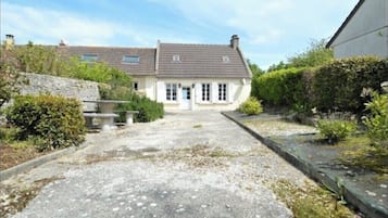 A two-story house with a gravel driveway leading to the entrance.
