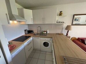 Cozinha compacta com máquina de lavar, pia e torradeira.