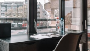Un escritorio moderno con una computadora, papeles y dos botellas de agua.