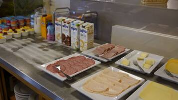 Un buffet con diverse pietanze, tra cui carni, formaggi e latticini.