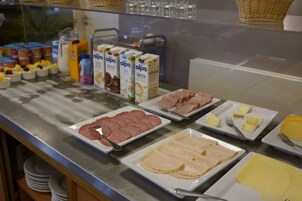 A buffet with various food items including meats, cheeses, and dairy products.