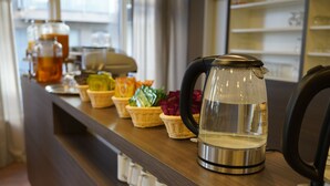Una estación de café con hervidor, teteras y diferentes bocadillos.