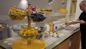 Un bufé con diversos alimentos, entre ellos frutas, pasteles y bocadillos empaquetados.