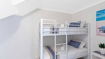 A bunk bed with a clock, pillows, and a blanket.