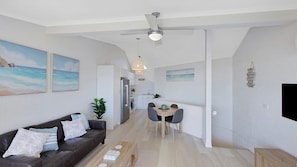 Un espacio habitable moderno con sofá, mesa de comedor y ventilador de techo.