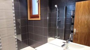A modern bathroom with a white sink, a glass shower enclosure, and a wooden door. - Renovated 3-star apartment in Les Gets, at the slopes, parking and wifi inclusive, for 8 pax (Les Gets)