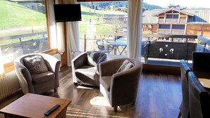 A cozy room with three armchairs, a wooden coffee table, and a TV mounted on the wall. - Renovated 3-star apartment in Les Gets, at the slopes, parking and wifi inclusive, for 8 pax (Les Gets)