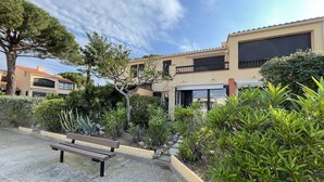 A courtyard with a bench, surrounded by well-maintained greenery and a building with a balcony. - Calm 2BR with terrace, AC and parking near beach (Saint-Cyprien)