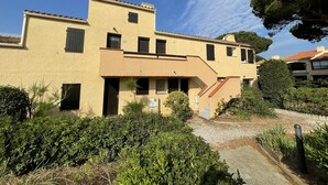 A two-story building with a flat roof, multiple windows, and a small staircase leading to the upper floor. - Calm 2BR with terrace, AC and parking near beach (Saint-Cyprien)