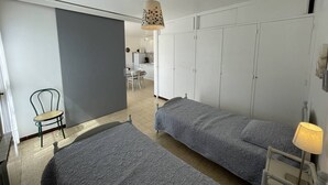 A room with two single beds, a chair, a desk, and a wardrobe.