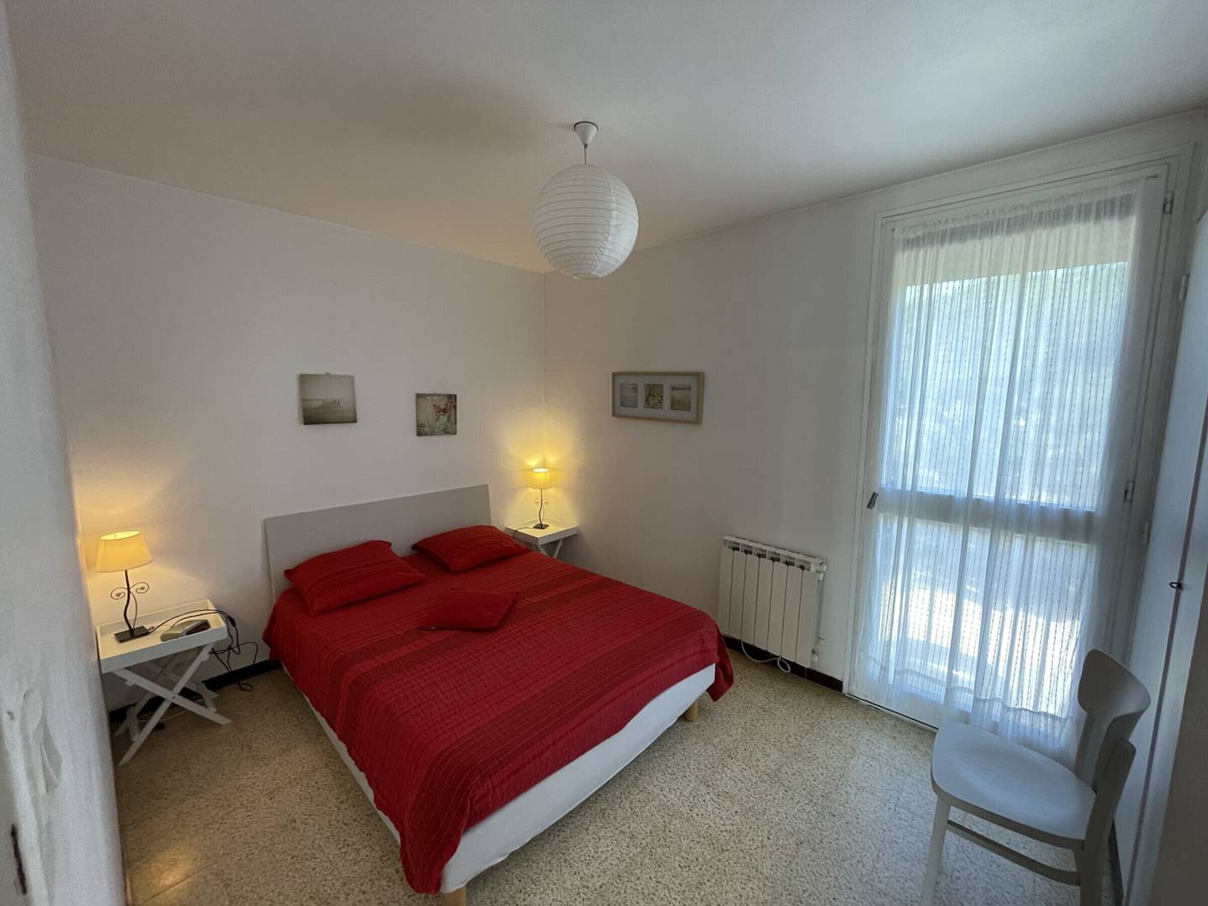 Une chambre avec un grand lit, deux lampes de chevet, un radiateur et une chaise.