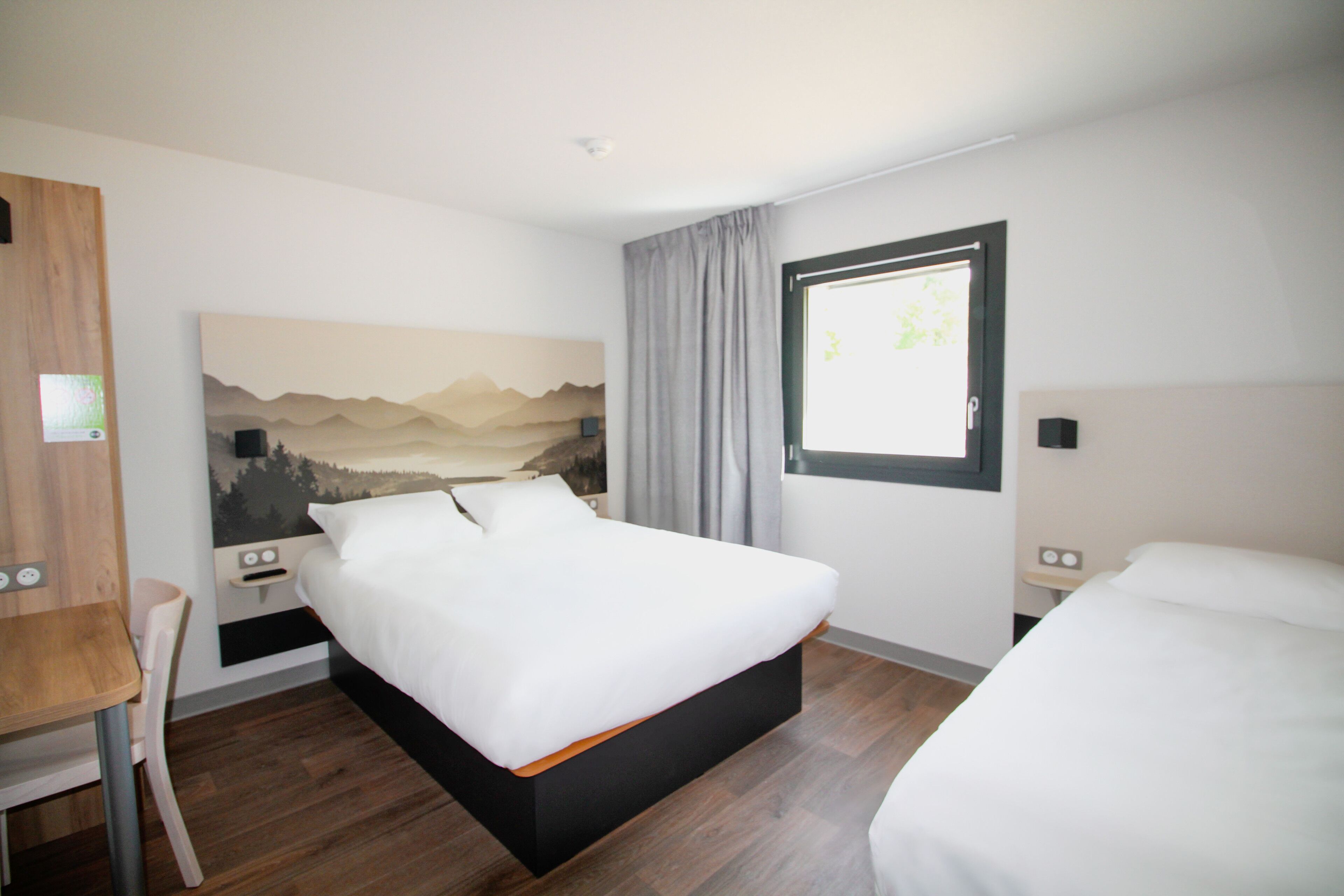 A hotel room with a bed, a desk, and a chair.