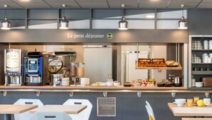 Una cafetería con mostrador de autoservicio, zona de mesas y un cartel de menú visible.
