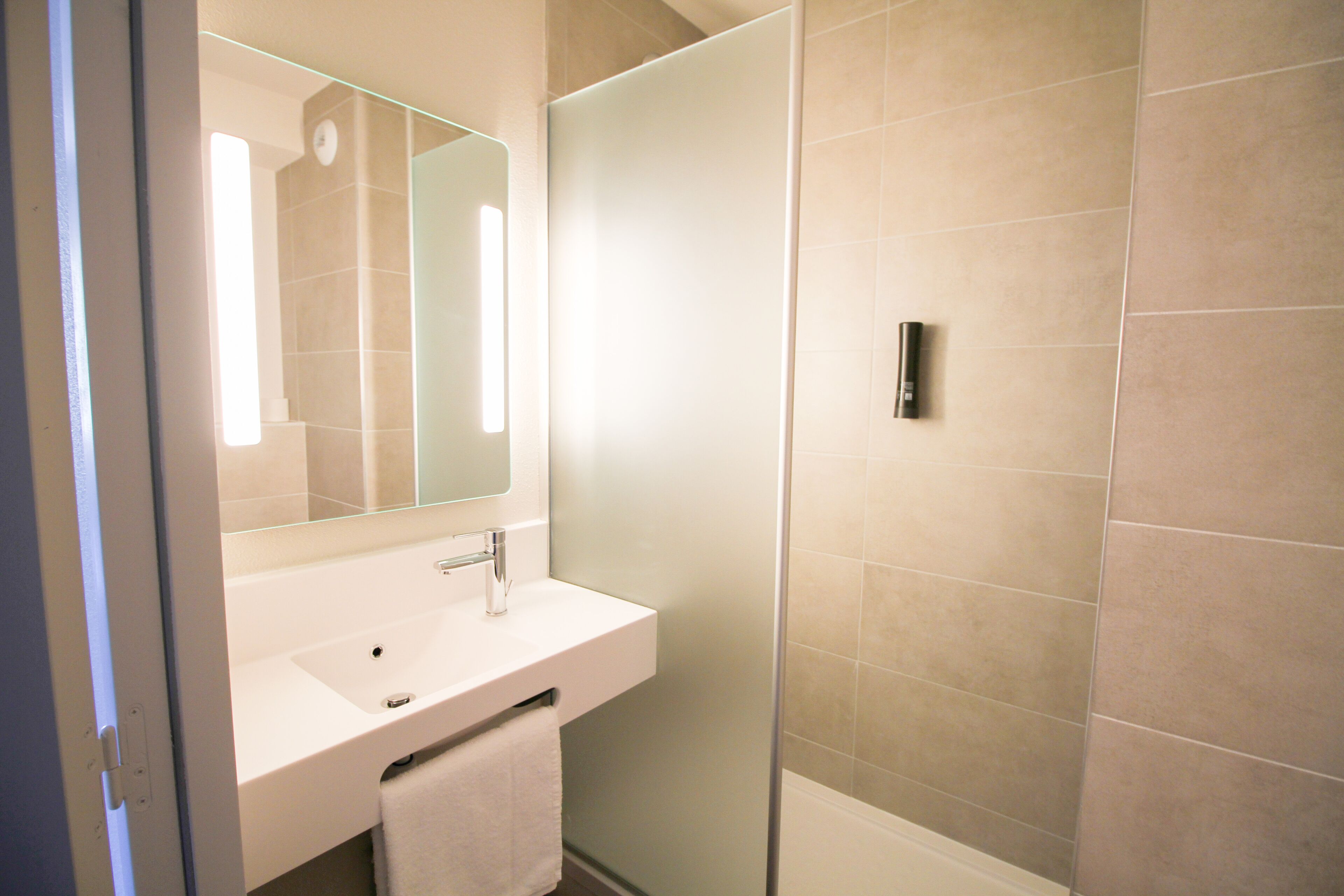 Un bagno con un lavandino bianco, uno specchio e una zona doccia.