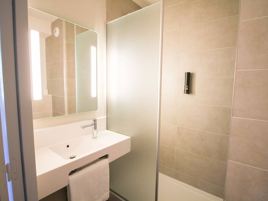 Un bagno con un lavandino bianco, uno specchio e una zona doccia.