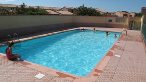 Une piscine rectangulaire à l’eau d’un bleu limpide, entourée d’une terrasse carrelée.