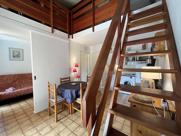 Ein kompakter Wohnbereich mit Essbereich, einer Couch, einer Treppe und einer Küchenzeile.