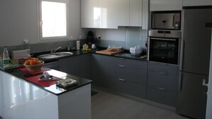 A modern kitchen with a central island, stainless steel appliances, and white cabinetry.