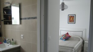 A bedroom with a bed, a bedside table, a nightstand, a bedside lamp, and a wall-mounted artwork.