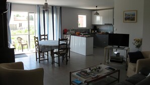A modern apartment with a dining area, kitchen, living room, and a balcony.