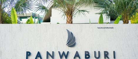 A sign for Panwaburi Beachfront Resort with palm trees in the background.
