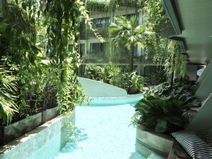 Un área de piscina interior con borde curvo, rodeada de exuberante vegetación y plantas.