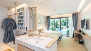 A modern hotel room with a large bed, a bathroom with a marble sink, and a view of greenery outside.
