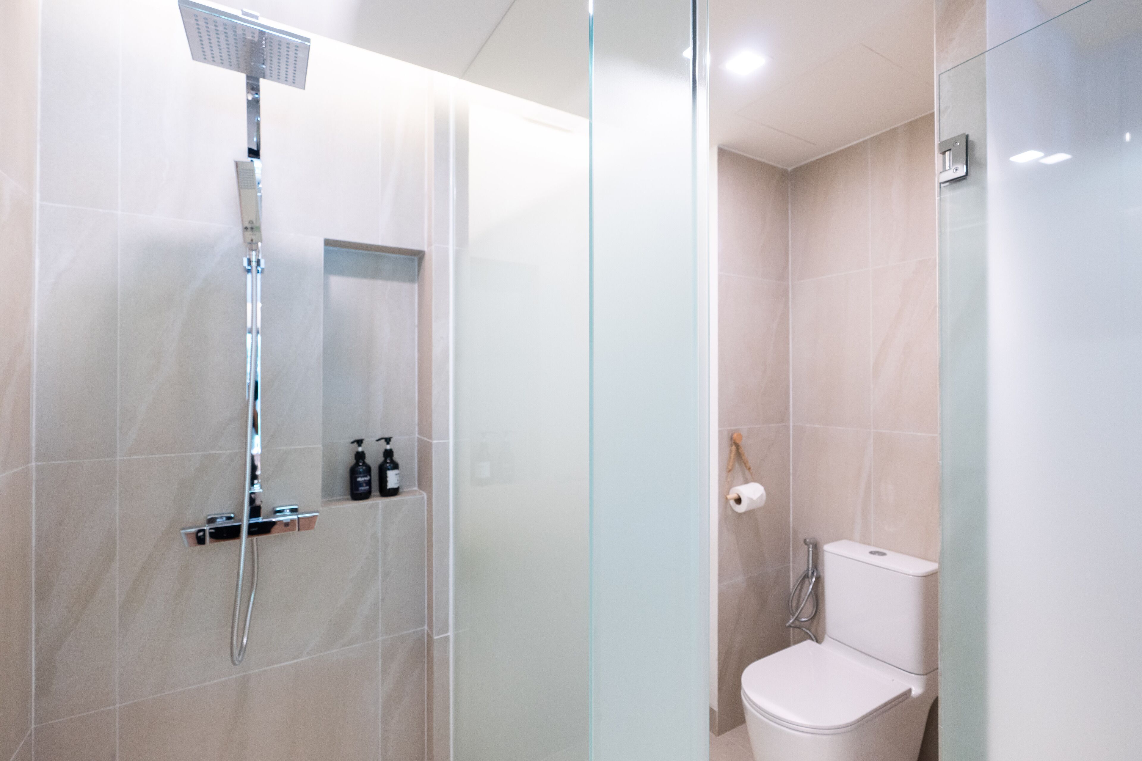 Un bagno moderno con cabina doccia in vetro, un water e un piccolo ripiano con articoli da toilette.