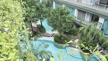 Un espace piscine aménagé sur le toit, avec des palmiers et une vue sur le bâtiment de l’hôtel.