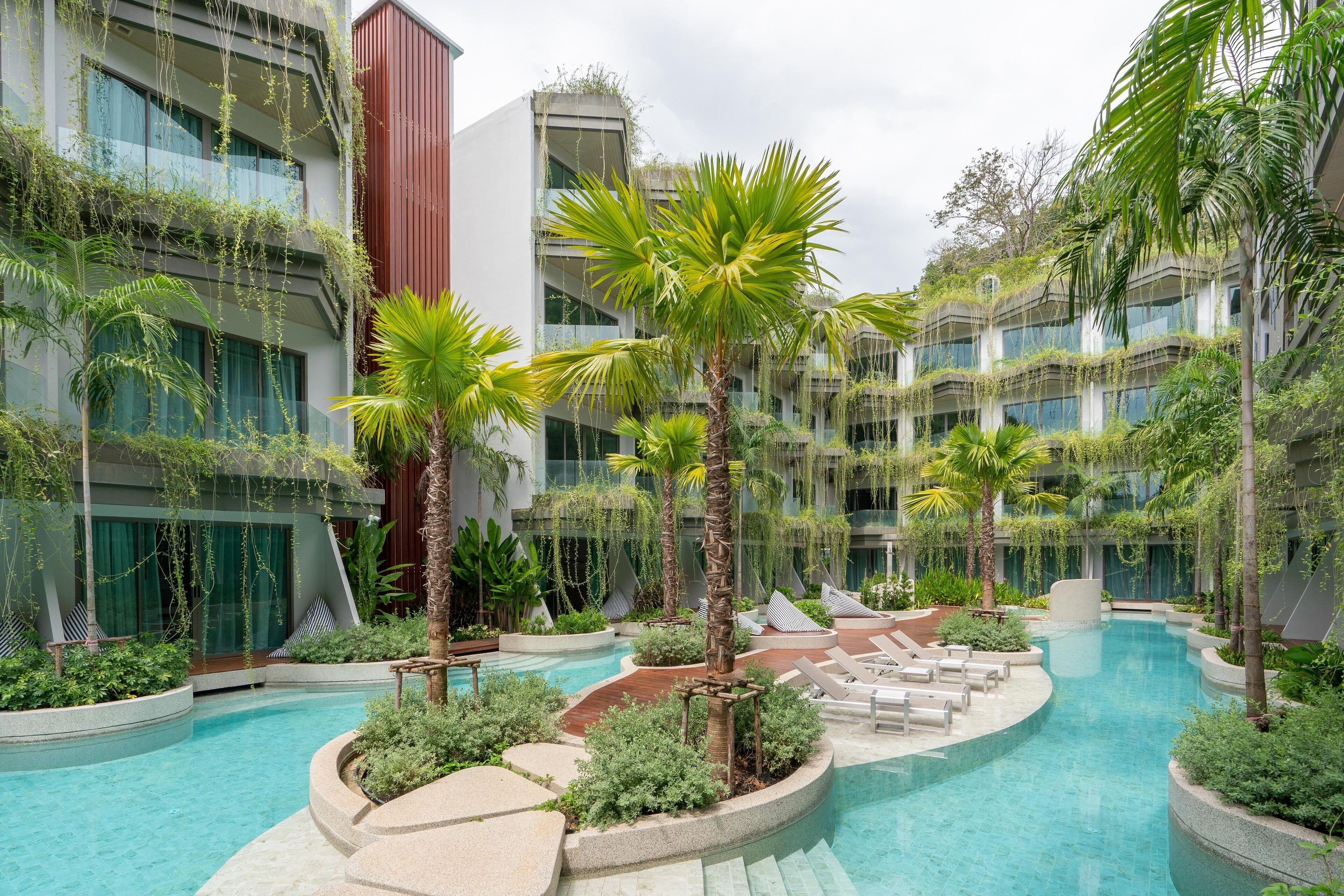 A hotel courtyard with a swimming pool, palm trees, and lounge chairs.